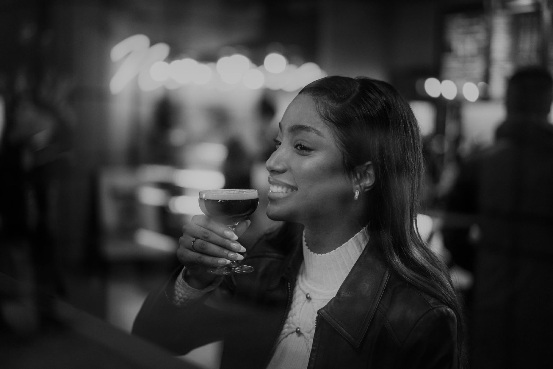 A customer with a coffee, shot in black and white against city bokeh.