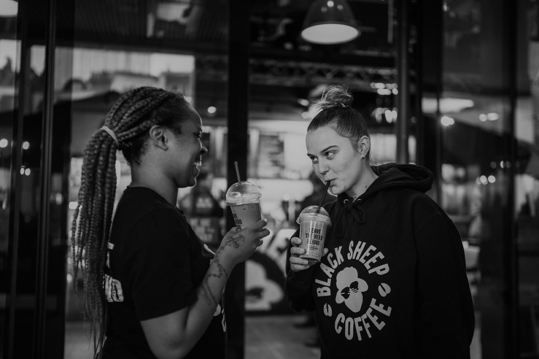 Two customers with branded cups, shot in black and white.