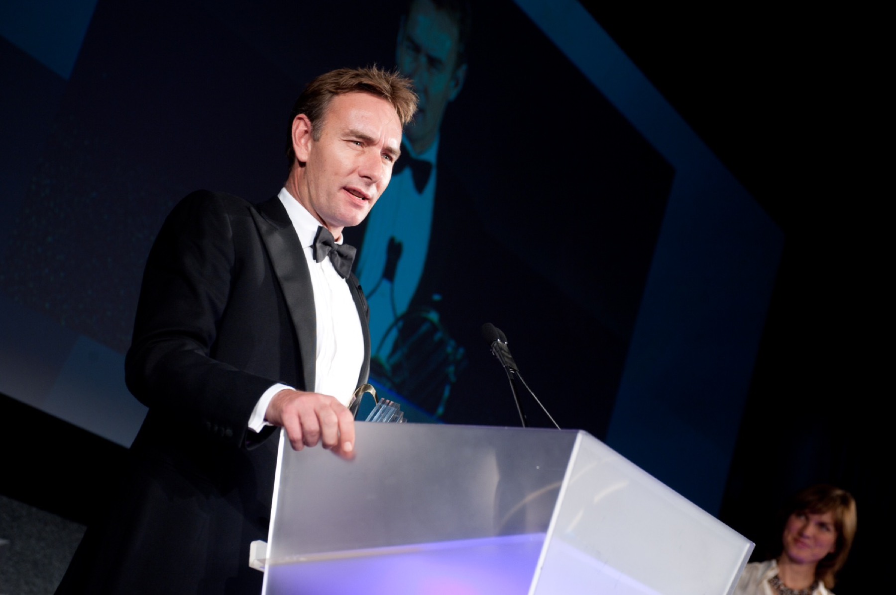 Christian speaking at a podium at an awards ceremony.