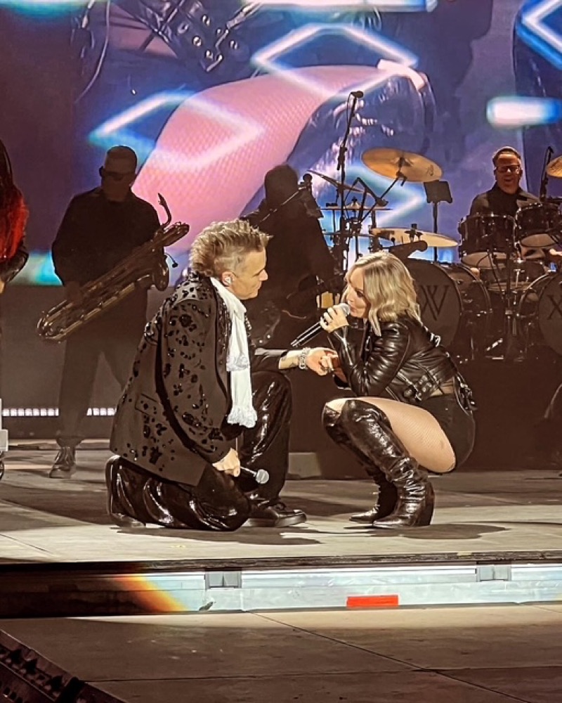 Louise Labelle on stage beside Robbie Williams.