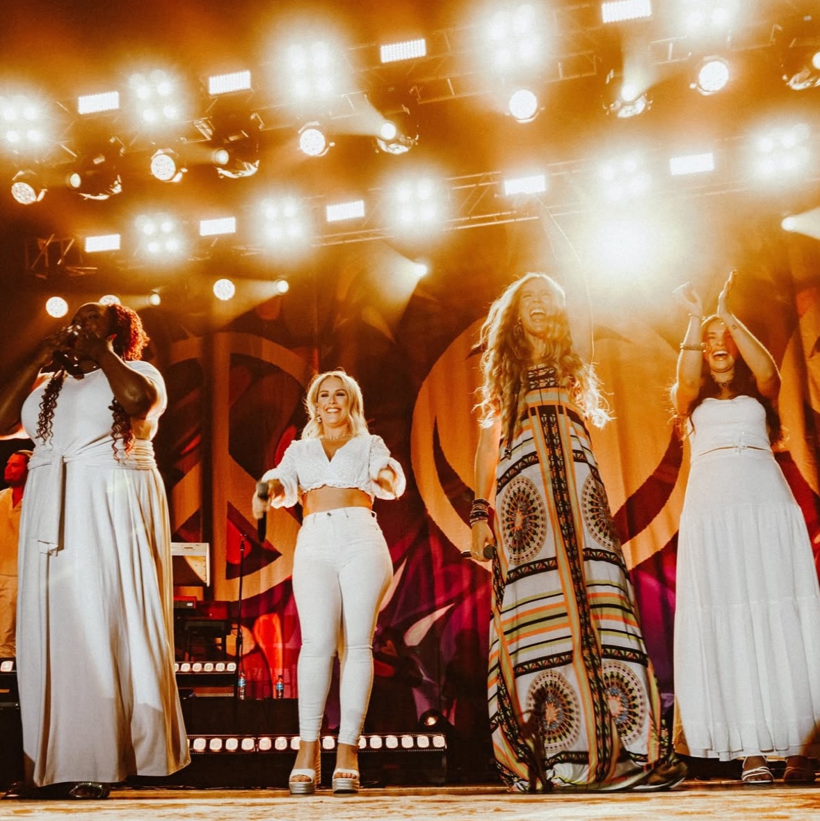 Louise on a festival stage with the band in white.