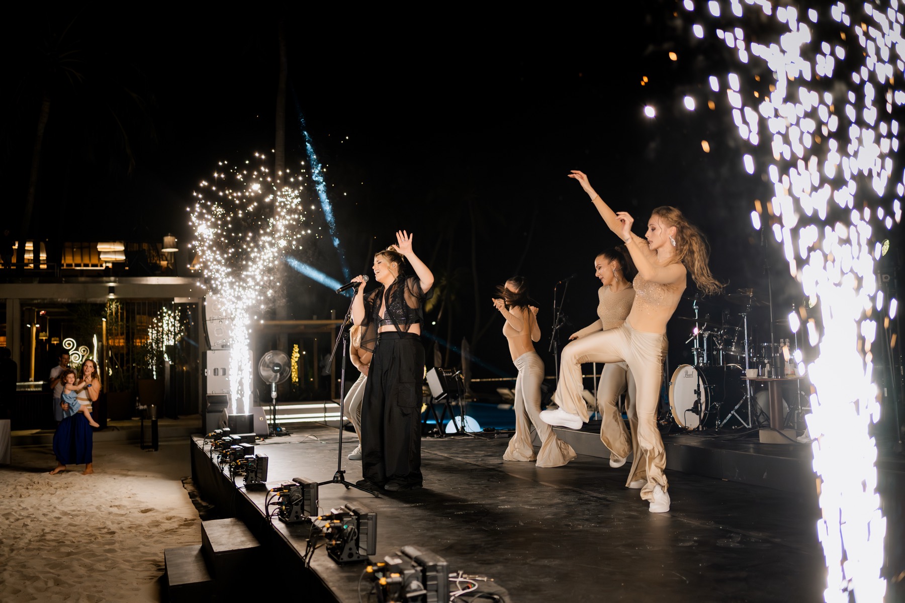Dancers on stage framed by pyrotechnic fountains.